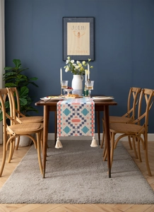 Detail of bohemian table runner with blue geometric patterns and cotton tassels on wood