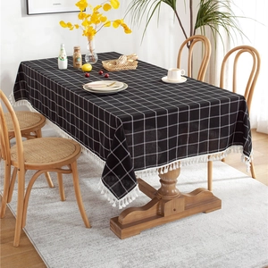 Rectangle black and white plaid tablecloth with tassels on a wooden dining table