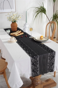 Detail view of black floral lace edges on a modern minimalist cotton table runner