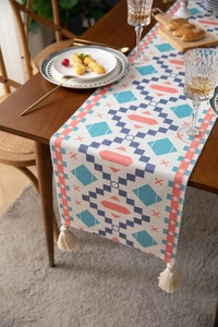 Close-up of geometric pattern weave and handmade cotton tassels on ethnic table runner