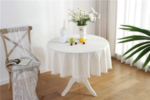 Detailed view of yellow daisy floral patterns and white pom-pom lace edge on cotton tablecloth
