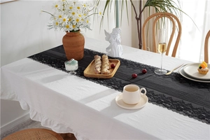 Detailed close-up of a black lace table runner featuring intricate floral patterns and scalloped edges