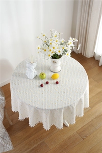 Detail view of yellow polka dot cotton tablecloth with white pom pom fringe edge
