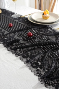 Detailed close-up of elegant black hollow lace table runner with floral patterns