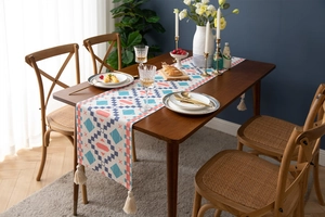Detail showing geometric patterns and cotton tassels on a bohemian style table runner