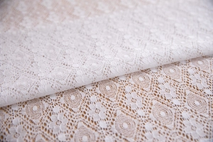 Detailed close-up of intricate white lace floral hollow pattern for tablecloth