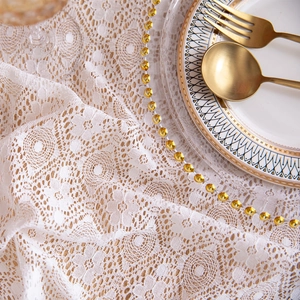 Close-up of white lace tablecloth with hollow floral patterns and elegant embroidery