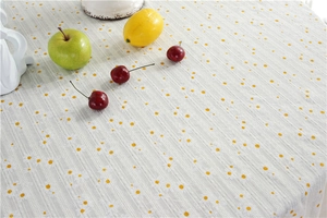 Close-up of yellow daisy floral pattern and striped jacquard texture on cotton tablecloth