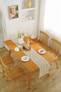 Detail of cream woven table runner with hollow crochet pattern and delicate fringe tassels