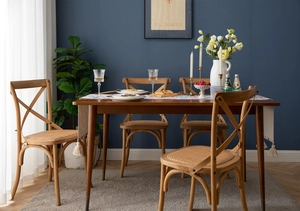 Detail of wooden chair with natural rattan seat and crossed back in a dining set