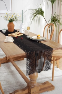 Close-up of elegant black lace table runner with floral embroidery and vertical mesh texture