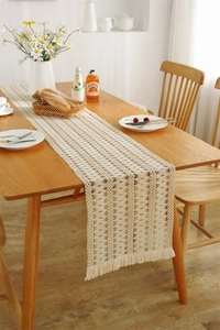 Detail of crochet cotton table runner with hollow geometric patterns and fringe edges