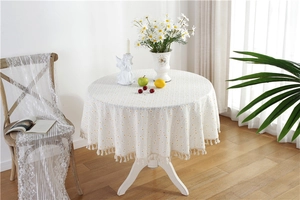 Detail of round cotton tablecloth with yellow polka dots and delicate white tassel edges