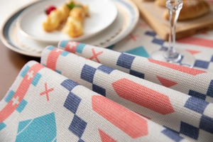 Macro detail of geometric woven table runner featuring colorful tassels and texture