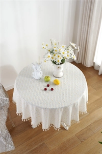 Detail of round cotton tablecloth with yellow polka dots and white fringe tassels