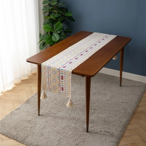 Detail of colorful geometric patterns and white cotton tassels on a woven table runner