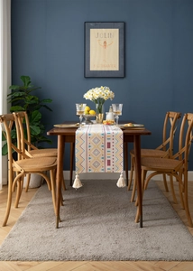 Detail of geometric bohemian table runner with tassels on a dark wood table
