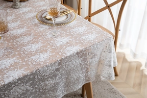 Détail de nappe en dentelle blanche avec broderies florales et texture en maille