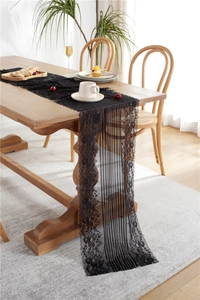 Close-up of black floral lace table runner with elegant scalloped edges on a wooden table