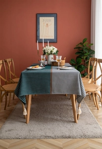 Close-up of geometric houndstooth and striped tablecloth with elegant cotton tassels