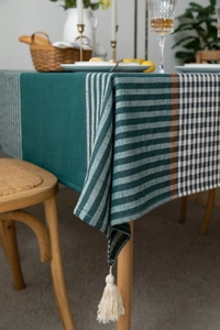 Detail of dark green geometric jacquard tablecloth fabric texture and cream fringe trim