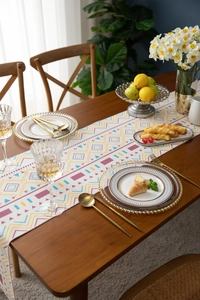 Detailed view of bohemian geometric pattern table runner with cotton fringe on wooden table