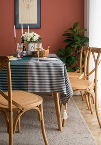 Detail of green and houndstooth tablecloth with decorative tassels on a dining table