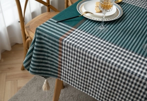 Detail of green and white plaid tablecloth with textured geometric patterns and tassels