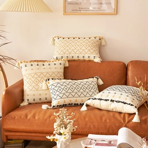 Dettaglio del copricuscino boho in maglia con ricami neri e nappe decorative gialle