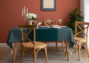 Detailed view of dark green tablecloth with white stripes and elegant beige tassels
