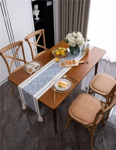 Detail of blue geometric table runner with off-white cotton tassels on wooden table