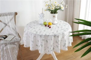 Close-up of white floral cotton tablecloth featuring elegant pom-pom lace edge detailing