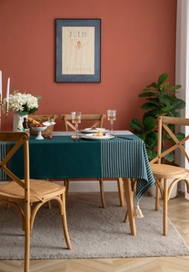 Close-up of deep green striped tablecloth with white tassels on a wooden table