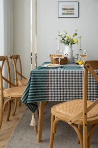 Detail of green striped and plaid tablecloth with elegant white fringe tassels