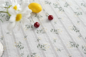 Detail of white cotton jacquard tablecloth with small yellow daisy flower embroidery