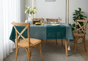 Detail of green and beige geometric jacquard tablecloth with tassel edge on a dining table
