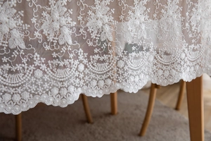 Détail de nappe en dentelle blanche avec broderie florale et bordure festonnée