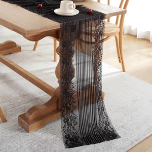Elegant black lace table runner with hollow floral patterns on a rustic wooden table