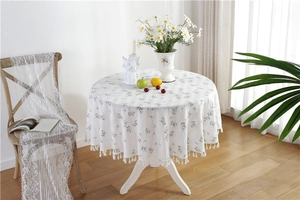 Detail of floral round cotton tablecloth with white tassels and fresh green daisy pattern