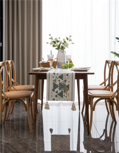 Dettaglio del runner da tavolo boho con triangoli colorati e nappe di cotone