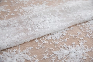 Gros plan sur la broderie de dentelle florale blanche sur maille pour table de mariage
