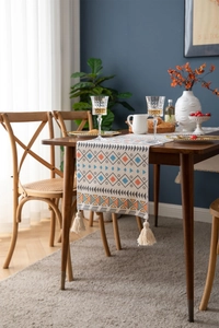 Close-up of geometric woven table runner featuring boho tassels and colorful patterns