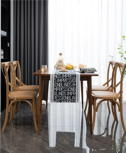Detail of black and white jacquard table runner with repeating typography on a wooden table