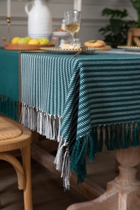 Close-up of dark green striped tablecloth with premium fringe tassels and heavy texture