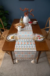 Close-up of bohemian table runner with colorful geometric patterns and white tassels