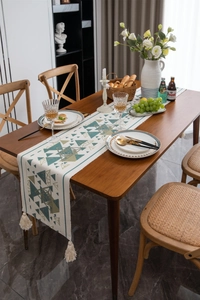 Dettaglio del runner da tavolo con motivi geometrici e nappe in cotone su legno