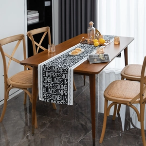 Detail of black and white jacquard table runner with English letters on a wooden dining table
