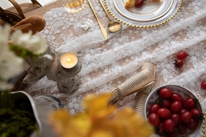 Détail de chemin de table en dentelle blanche avec motifs floraux et bords festonnés