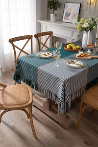 Detail of dark green and cream houndstooth tablecloth with woven fringe tassels