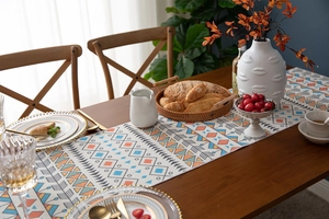Macro detail of geometric patterns and cotton tassels on a bohemian table runner